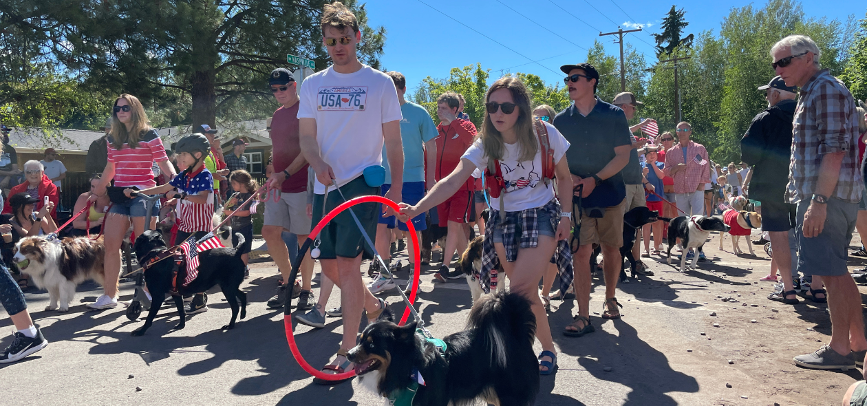 large parade crowd with American flag decorations and a young couple with dog in foreground