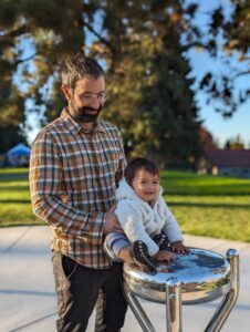 father and child playing on a music instrument at Juniper Park