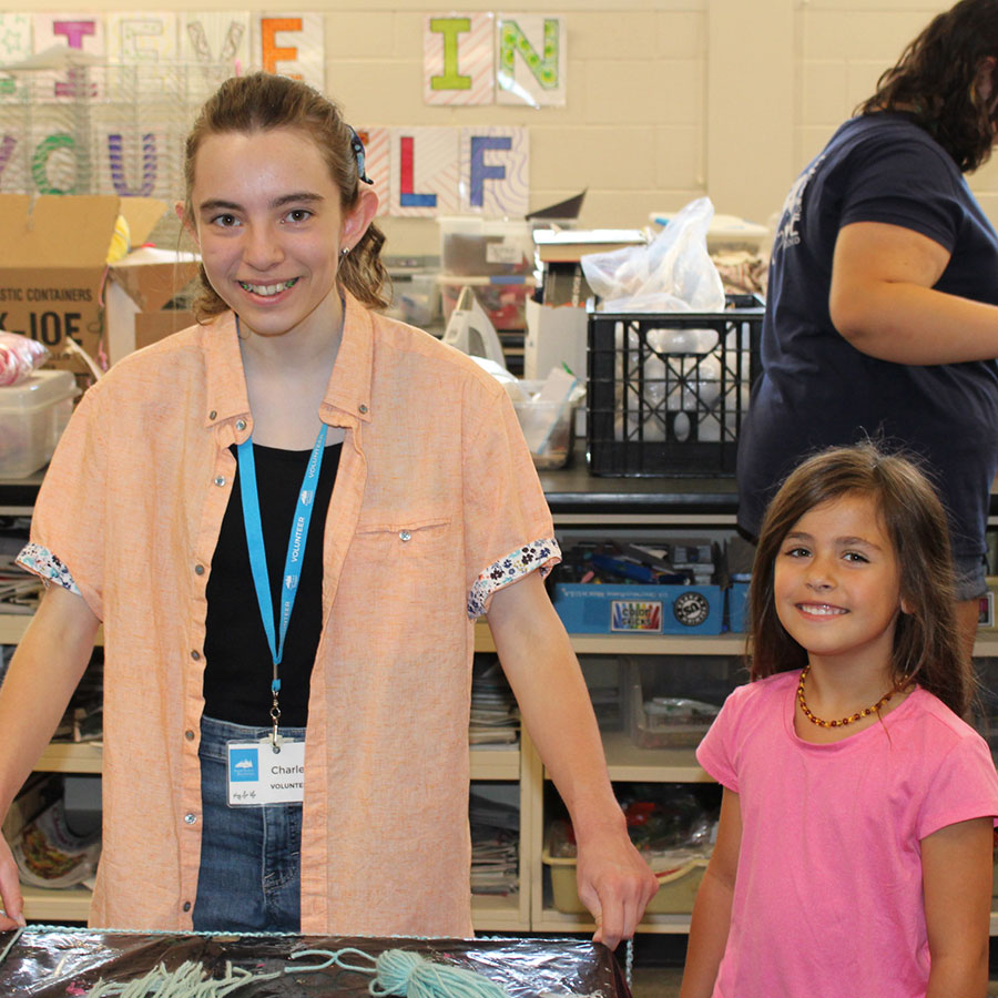 A teen volunteer helping a young child at a BPRD art program.