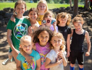 A group of young girls smile at the camera while enjoying a sunny day at Kids Inc.