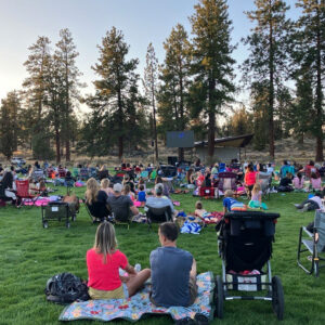 Photo of the Alpenglow lawn covered in people in with blankets and lawn chairs watching a movie in the park.