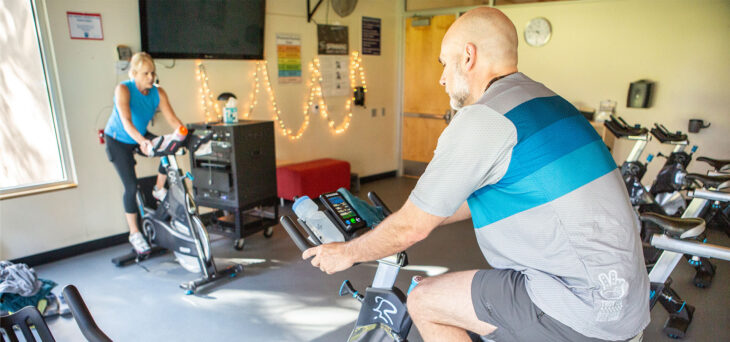 An instructor leads an indoor cycling class.