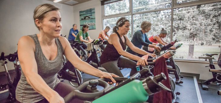 A group of adults in an indoor cycling class.