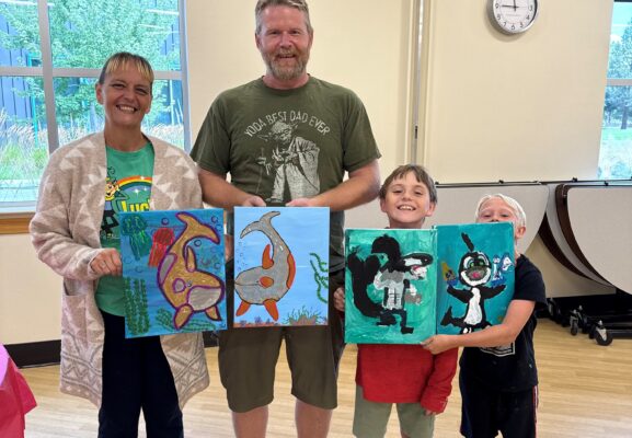 Family shows off thier paintings at a With A Child art class.