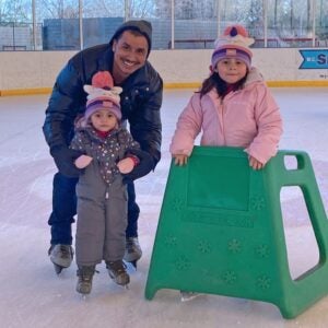 A father and two children smile a the camera durring an ice skate session at the Pavilion