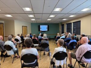 people seated watching a presentation at Larkspur Community Center