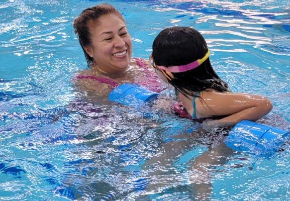 Caretaker and child at Spanish language swim lessons class.