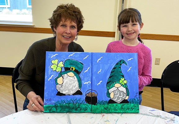 Guardian and child show off their art at a With A Child painting class