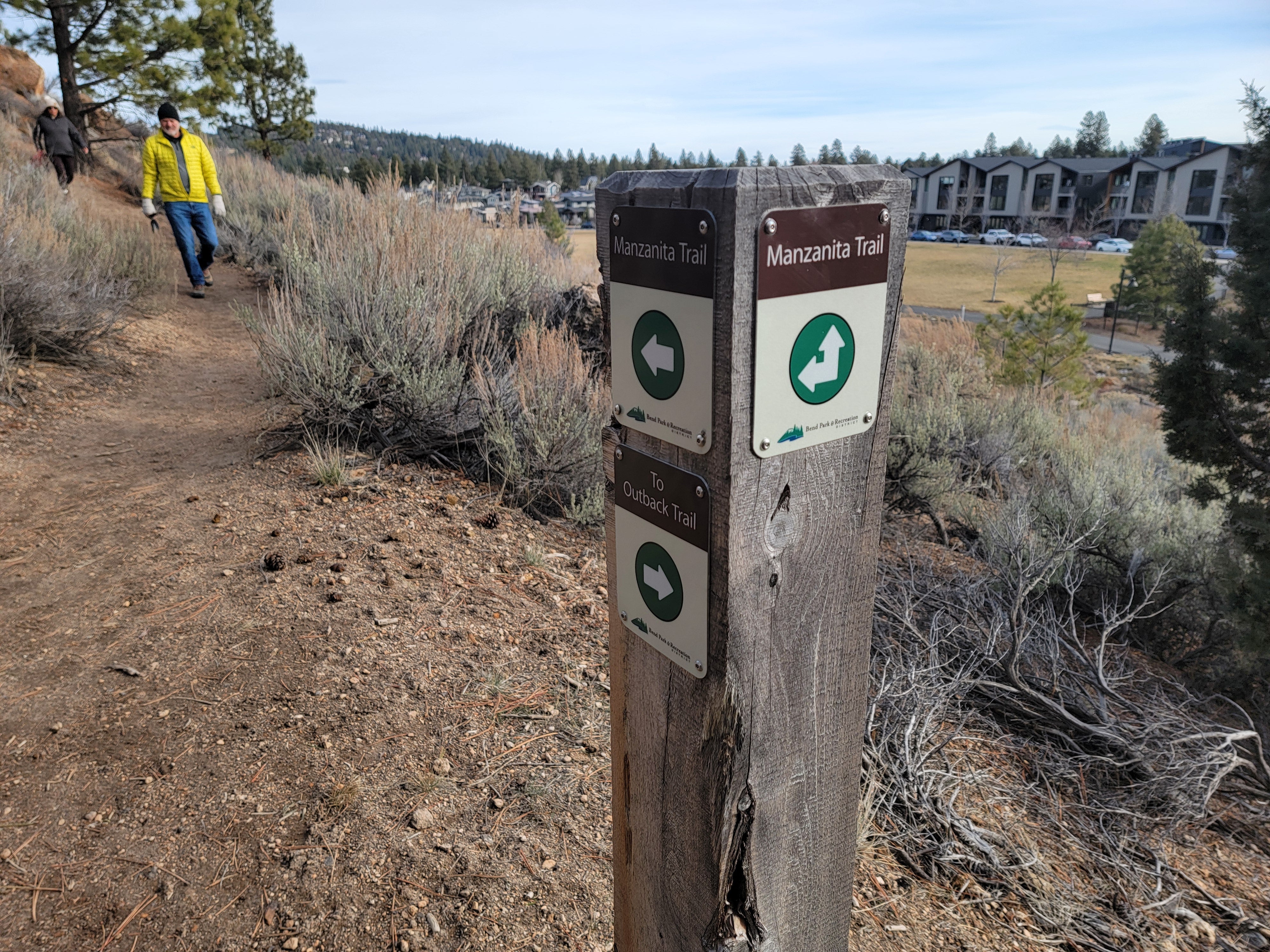 a trail post on the edge of a trail with a hiker in the distance