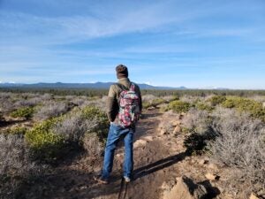 hiker on trail looking across open space toward Cascade mountains
