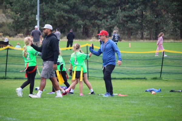 Volunteer coaches give high-fives to players at at BPRD flag football game.