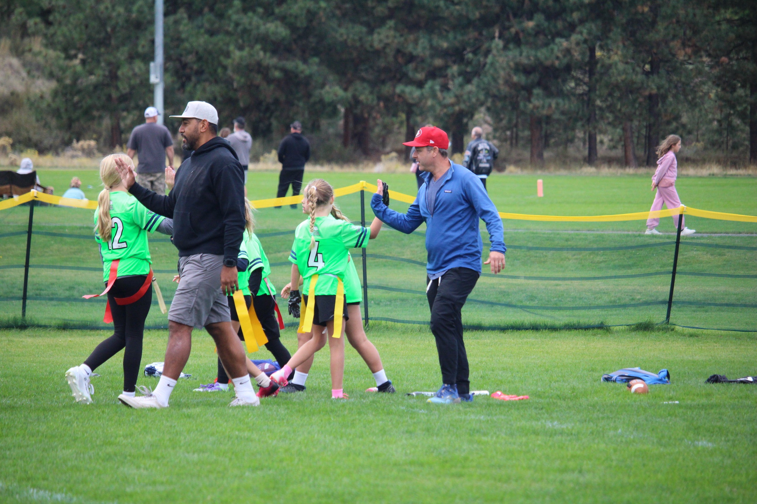 Volunteer coaches give high-fives to players at at BPRD flag football game.