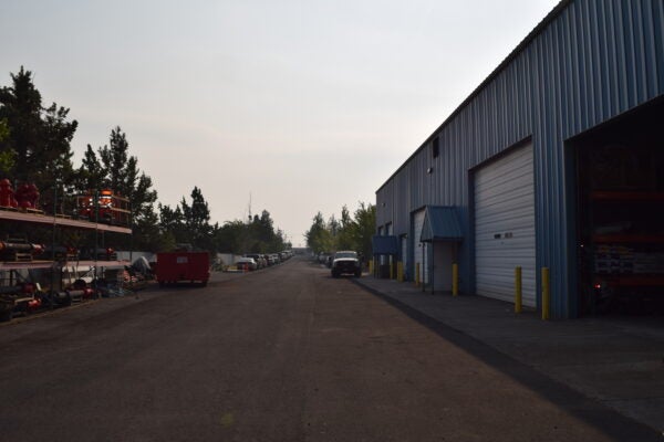 exterior of facility at Boyd Acres purchased by BPRD from the City of Bend for offices, operations and maintenance. Photo is vehicles, shop bay and building with no people.