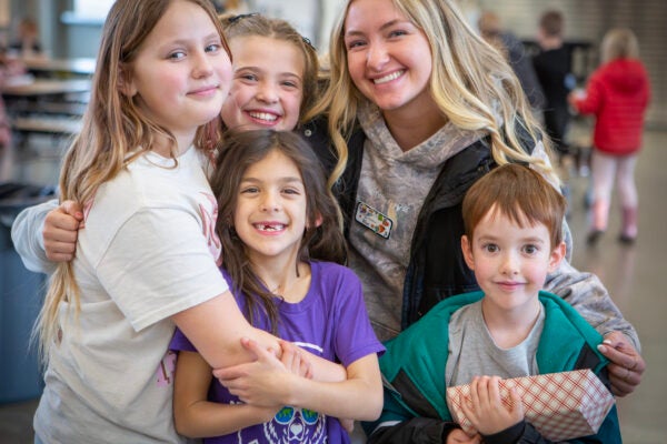 Adult youth recreation leader smiling with children in Kids Inc.